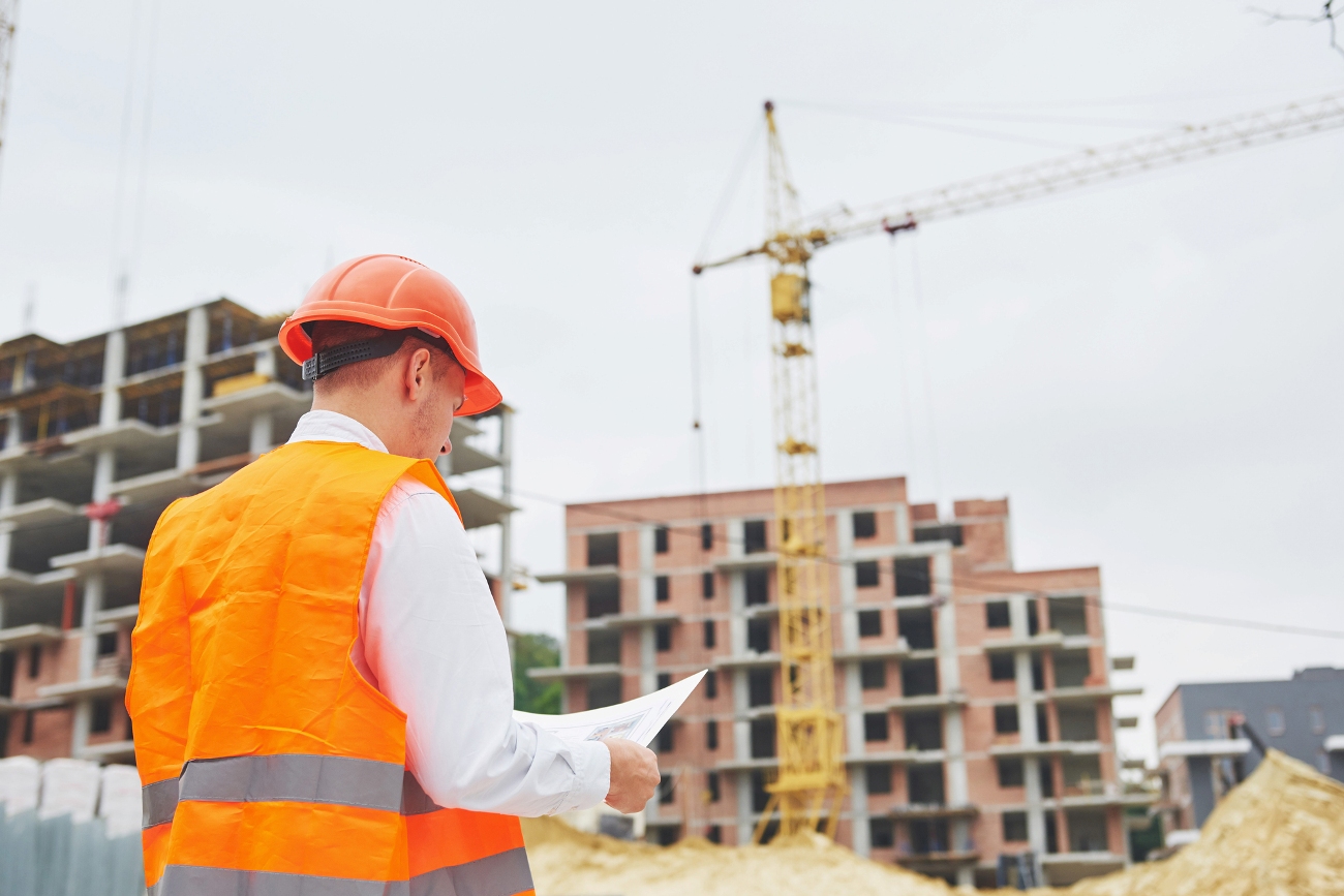 építész nézi a terveket, épülő lakóházak saruval