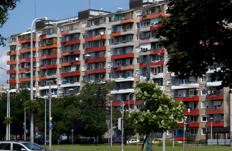 piros erkélyes lakótömb homlokzata fák között